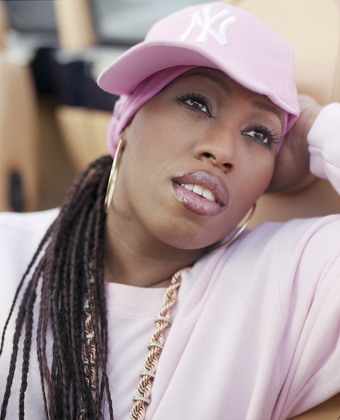 Portrait of Missy Elliot wearing a pink cap and jumper, looking into the distance.